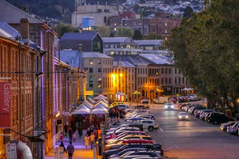 People strolling in Salamanca Place on a clear autumn evening after collecting their campervan hire Hobart Airport.